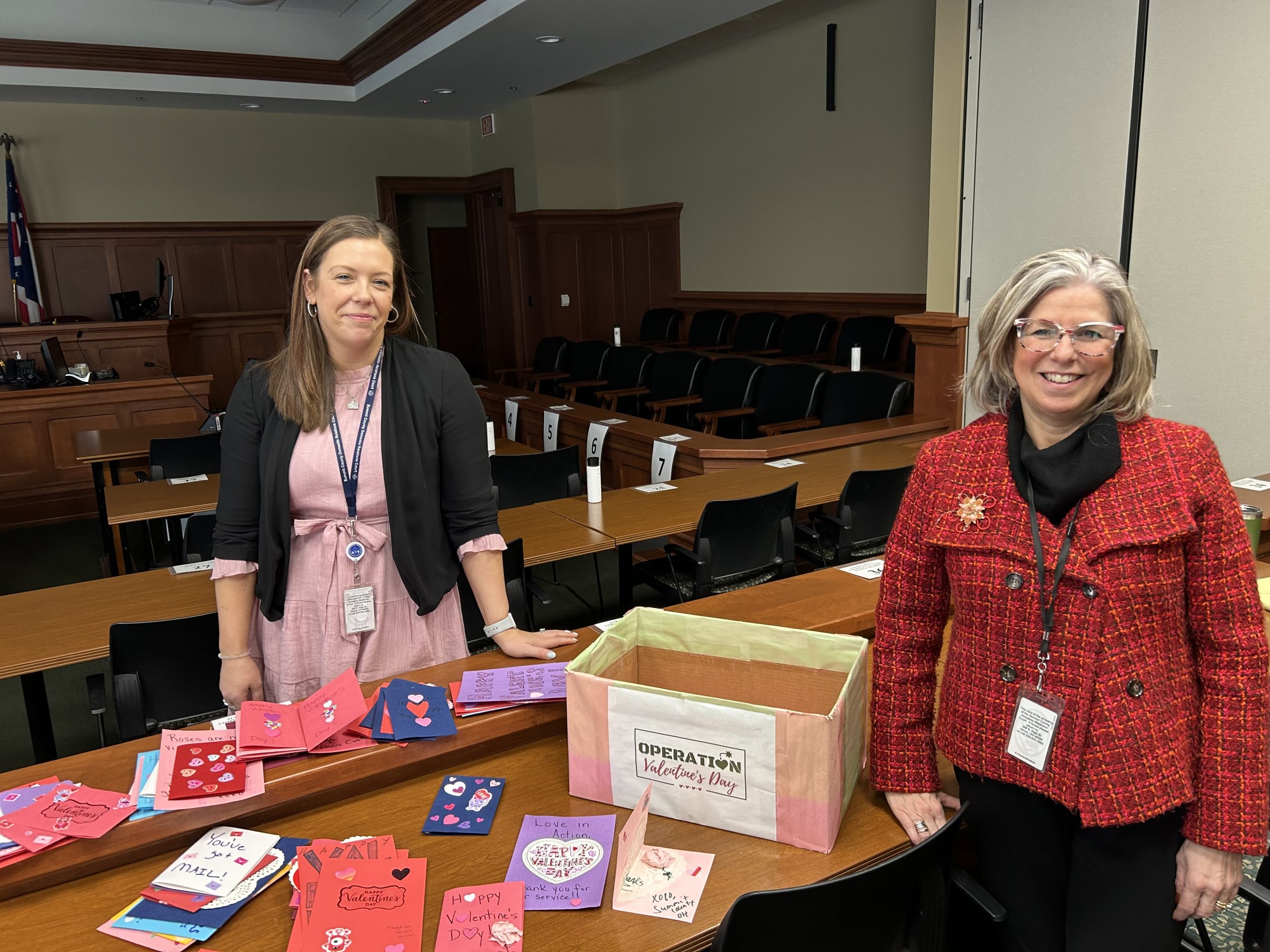 Operation Valentine 2025 - Bailiff and Judge Bailiff and Program Co-Founder Claire McIntire with Judge Katarina Cook next to Valentine Day Cards for Troops